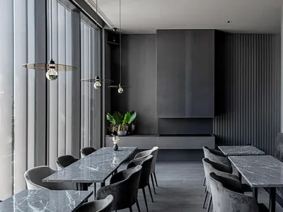 A modern restaurant with sleek marble tables and chairs, featuring industrial-style lighting and minimalist design.