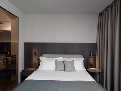 Minimalist bedroom featuring a gray fabric bed with white bedding and a dark gray wooden headboard.