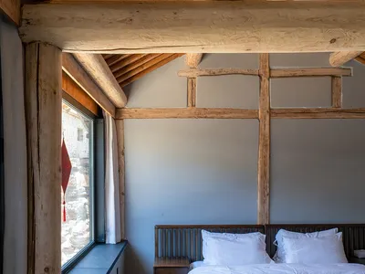 Modern barn-style bedroom featuring a wooden bed frame and rustic wooden beams on the ceiling.