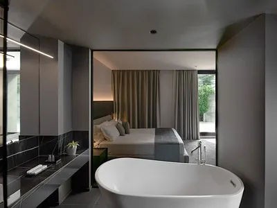 A modern bathroom bedroom suite featuring a concrete countertop and light gray curtains.