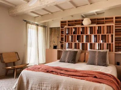 A cozy bedroom with a wooden bookshelf as the focal point, featuring comfortable bedding and a rustic chair.