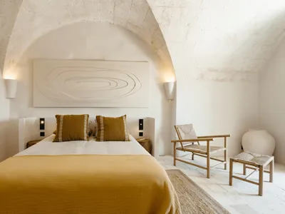 A minimalist bedroom with a yellow bedspread and wooden furniture.