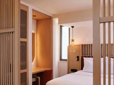 Modern minimalist bedroom featuring a white bed with wooden elements.