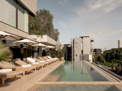 Outdoor hotel rooftop pool with concrete deck and lounge chairs.