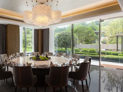 Modern dining room with a large round table set for a meal, featuring contemporary furniture and a minimalist design aestheti