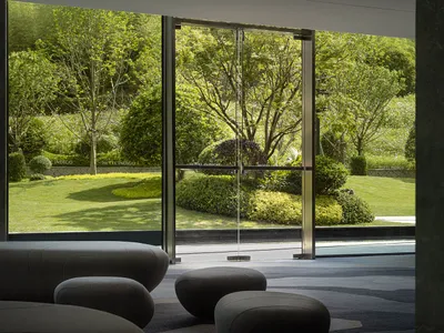 A modern hotel lobby featuring glass, concrete, and greenery