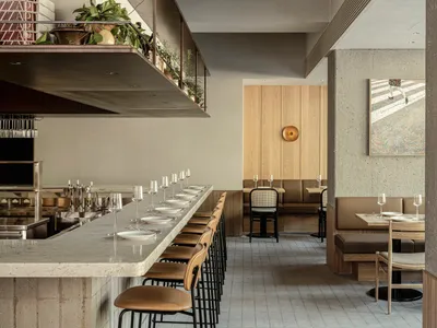A modern restaurant interior with concrete walls and wooden seating