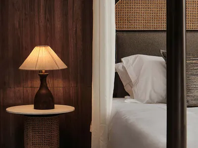 A cozy bedroom with wooden paneled walls, a canopy bed, and a table lamp.