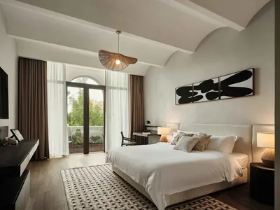 A minimalist bedroom featuring white fabrics on the bed and a wooden floor.