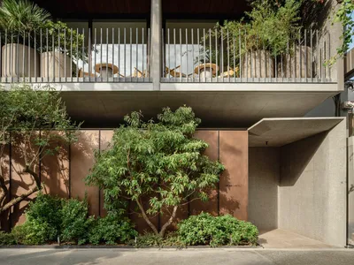 Modern hotel entryway with concrete facade and greenery.