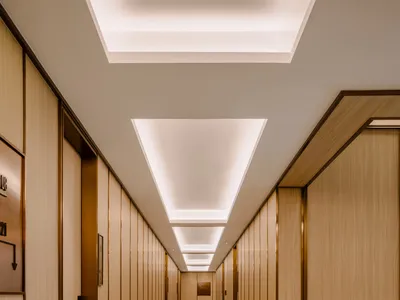 Modern hotel hallway featuring marble walls and a wooden floor.