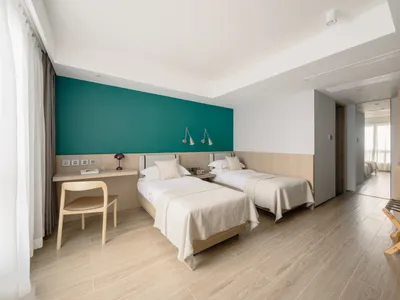 A modern minimalist bedroom with twin beds, wooden headboards, and a green accent wall.
