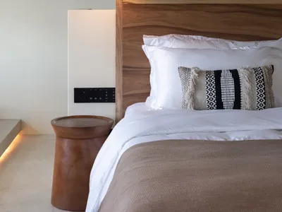 Modern, minimalist bedroom featuring a wooden headboard and textured blanket.