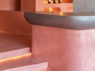 Minimalist restaurant bar with concrete walls and a curved bar counter.