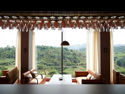 A modern restaurant interior with a glass ceiling overlooking lush green hills.