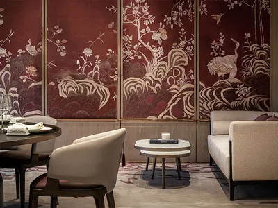 A modern restaurant interior featuring white chairs, a beige sofa, and a round dining table set with plates, glasses, and tow