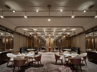 Industrial-style restaurant interior with metal and glass elements, featuring round tables, modern seating, and minimalist de