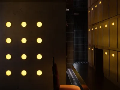 Modern hotel lobby interior with metal wall panels, wooden furniture, and warm yellow lights.