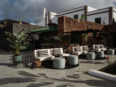 Outdoor seating area of a hotel patio with concrete floors, white sofas, and greenery.