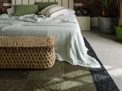 Minimalist bedroom with linen, woven rattan, and stone wall