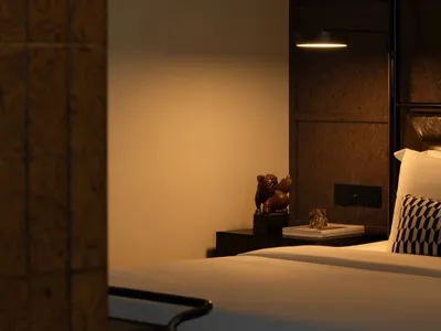 Minimalist bedroom with wooden details, lit by warm ambient lighting.