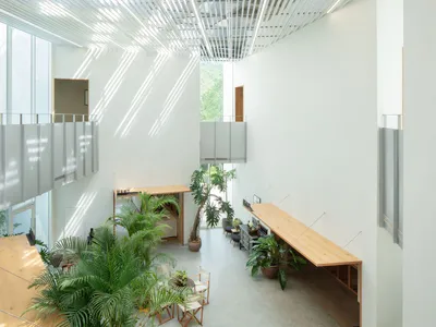 簡約風格的餐廳大廳，搭配木質家具與玻璃隔間，高挑天花板與充足自然光線。