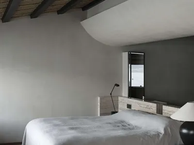 現代極簡臥室室內，採用混凝土飾面，窗外可見海洋景觀。
