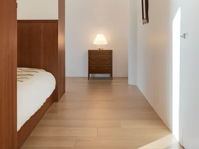 Modern minimalist bedroom featuring wooden furniture and a warm, cozy atmosphere.