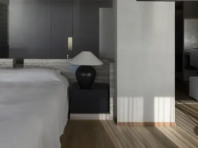 A modern minimalist bedroom featuring a large bed with a concrete frame and a black lamp on a nightstand.