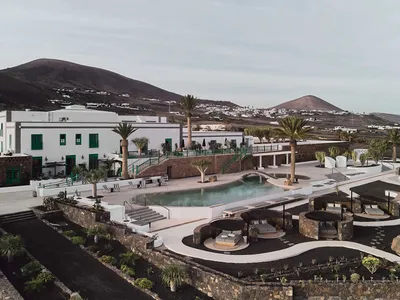 Modern resort hotel featuring a minimalist pool area with concrete, glass, and palm trees.