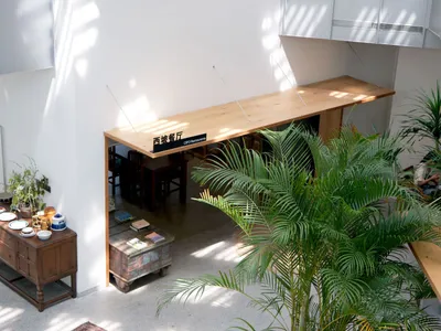 A modern restaurant interior with wooden tables and green plants.