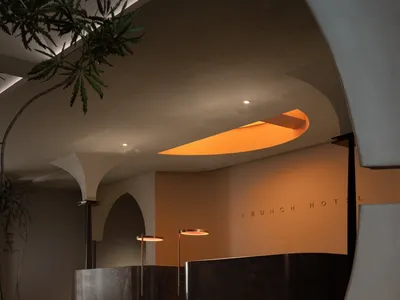 A sleek, modern hotel reception desk with wooden and concrete materials in a luxurious interior space.