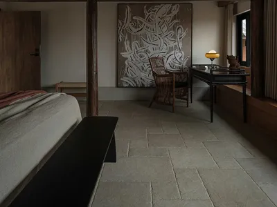 A modern minimalist bedroom featuring a floating bed, exposed wooden beams, and a large abstract painting.