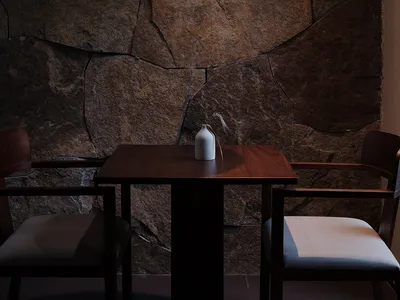 Modern restaurant interior featuring stone wall, wooden table, and pendant light.