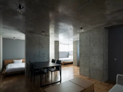 A modern bedroom with concrete walls and minimalist furniture.