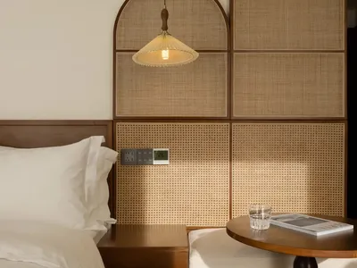 A minimalist bedroom featuring wood elements and a hanging light fixture.