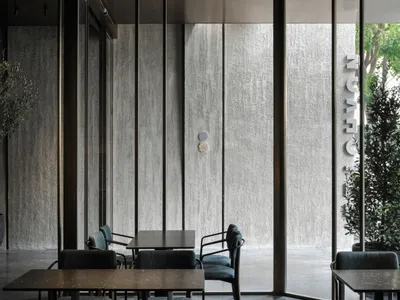 Concrete restaurant interior with industrial design elements, featuring industrial-style tables and chairs.