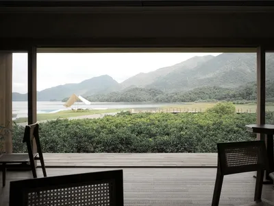 A minimalist interior design with a view of a living room through a large window overlooking a beautiful panorama of mountain