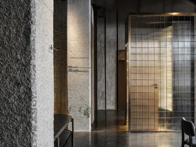 A minimalist restaurant interior with metal, glass, and concrete finishes, featuring a modern design aesthetic.