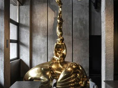 A modern restaurant interior showcasing a large, metallic sculpture in the center of the room.