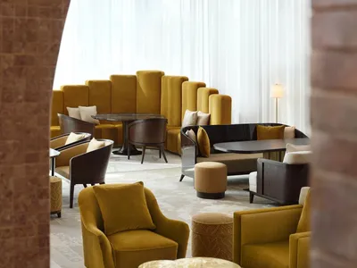 A modern hotel lounge decorated with vibrant velvet cushions and elegant marble furniture.