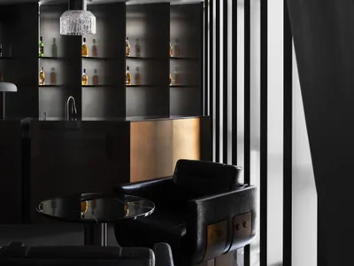 A modern hotel suite bar featuring black walls, metal accents, and a large window.