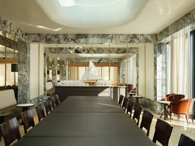 A modern restaurant interior with marble walls and a large skylight.