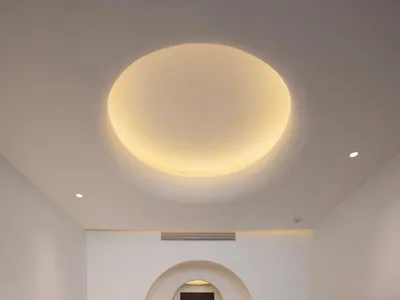 Modern minimalist bedroom featuring a king-sized bed with neutral bedding and a circular light fixture above