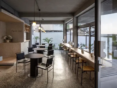 Modern restaurant interior with concrete walls, metal tables, and minimalist decor.
