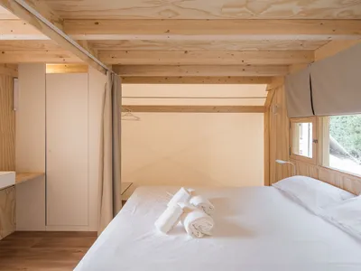 A minimalist bedroom with wooden elements, white linens, and a simple design.