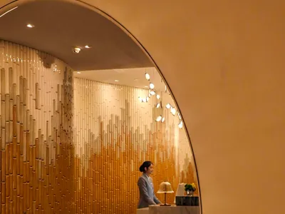 A modern hotel lobby featuring marble tiles, wooden panels, and ambient lighting.