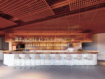 A minimalist bar counter with metal stools and a metal ceiling grid