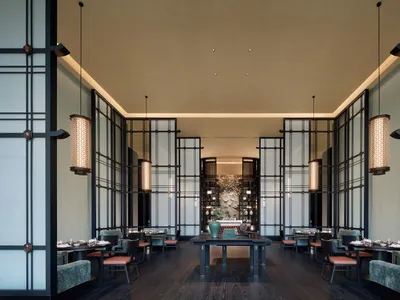 A modern restaurant interior featuring dark wood floors, glass partitions, and metal frame chairs.