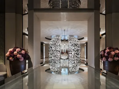 A grand, elegant hotel lobby featuring a large, ornate glass sphere at its centerpiece.